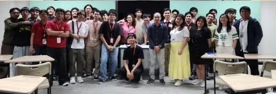 A group photo of bootcamp participants standing between classroom desks.