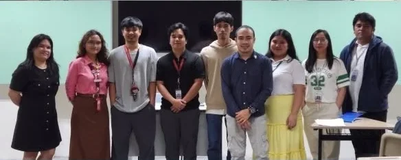 Nine people standing in a line at the front of a classroom, faculty among them.